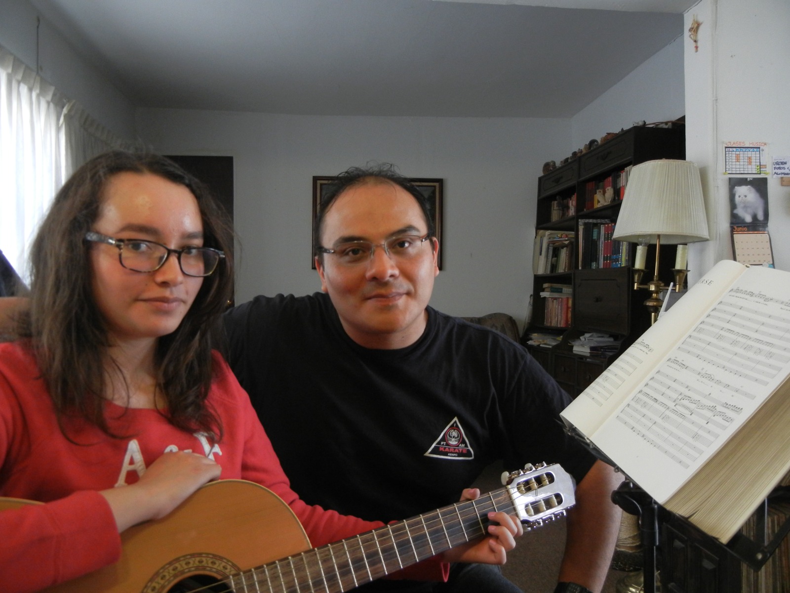 Alumna practicando guitarra en familia con partitura en Academia 909